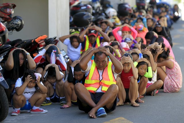 Residents cover their heads with their hands during a simultaneous earthquake drill inside the police headquarters in Quezon city, metro Manila April 21, 2016. (Photo by Romeo Ranoco/Reuters)