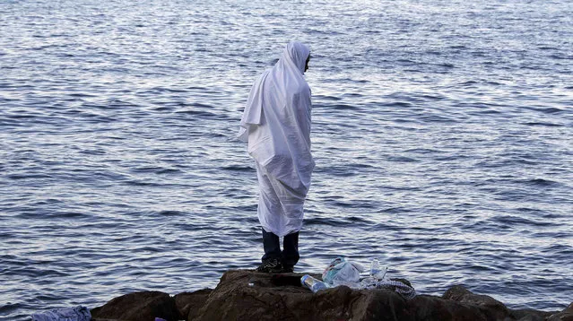 A migrant wrapped in a white a blanket stands on the rocks of the seawall at the Saint Ludovic border crossing on the Mediterranean Sea between Vintimille, Italy and Menton, France, June 17, 2015. Police on Tuesday began hauling away mostly African migrants from makeshift camps on the Italy-France border as European Union ministers met in Luxembourg to hash out plans to deal with the immigration crisis.    REUTERS/Eric Gaillard  