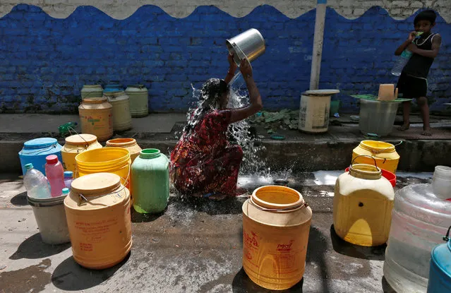 A woman bathes at a roadside municipal tap in a slum area on a hot summer day on the outskirts of Kolkata, India, April 22, 2016. (Photo by Rupak De Chowdhuri/Reuters)