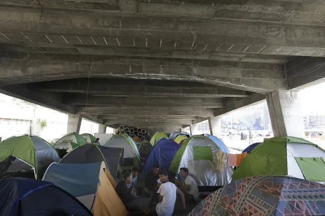 Afghan migrants play cards outside their tents under a bridge at the port city of Piraeus, Greece, on Monday, April 25, 2016. (Photo by Thanassis Stavrakis/AP Photo)