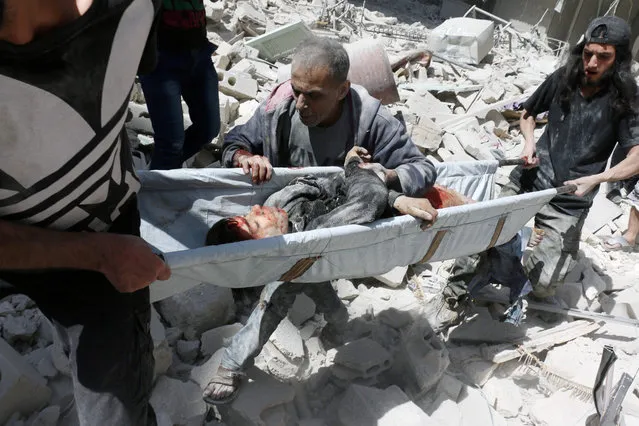 A man follows rescuers carrying the body of a boy on a stretcher following a reported air strike on the rebel-held neighbourhood of al-Kalasa in the northern Syrian city of Aleppo, on April 28, 2016. (Photo by Ameer Alhalbi/AFP Photo)