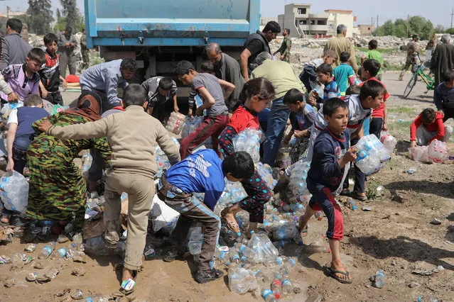 Displaced Iraqi children receive water on a street in Mosul, Iraq, April 7, 2017. (Photo by Marko Djurica/Reuters)