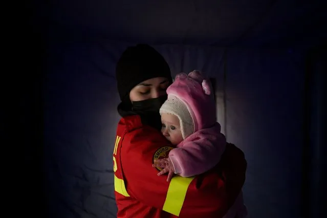 An employee from the Emergency Situation Inspectorate soothes the crying baby of a family fleeing the conflict from neighbouring Ukraine at the Romanian-Ukrainian border, in Siret, Romania, Saturday, February 26, 2022. Romania, which shares around 600 kilometres (372 miles) of borders with Ukraine to the north, is seeing an influx of refugees from the country as many flee Russia's attacks. (Photo by Andreea Alexandru/AP Photo)