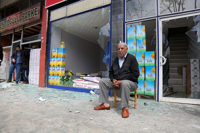 A shop owner sits near the site after an explosion in Diyarbakir, Turkey, Tuesday, April 11, 2017. An explosion inside a workshop where a police armored vehicle was being repaired killed one man and injured a number of other people, Turkish police said Tuesday. The blast in the mainly Kurdish city of Diyarbakir caused part of the workshop – an annex to the city's main police headquarters – to collapse. (Photo by AP Photo/Stringer)