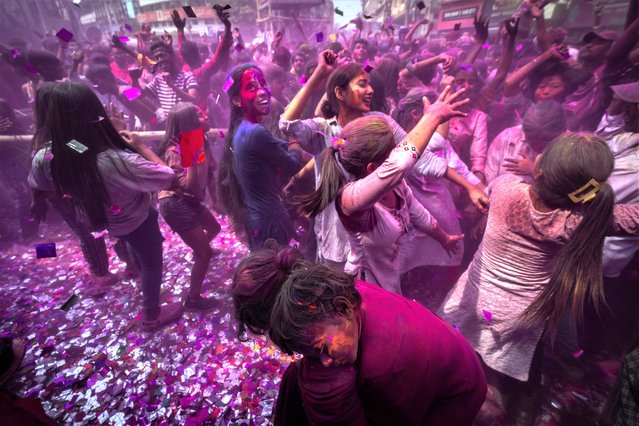 People celebrate Holi, the festival of colors on a street in Guwahati, India, Wednesday, March 8, 2023. Millions of Indians on Wednesday celebrated the “Holi” festival, dancing to the beat of drums and smearing each other with green, yellow and red colors and exchanging sweets in homes, parks and streets. Free from mask and other COVID-19 restrictions after two years, they also drenched each other with colored water. (Photo by Anupam Nath/AP Photo)