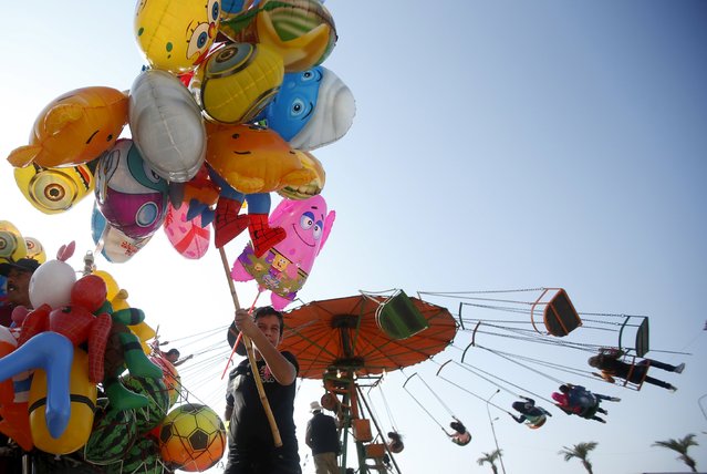 Street vendors sell balloons as people enjoy a swing ride as they celebrate tthe first day of the Muslim holiday of Eid al-Fitr, which marks the end of the holy month of Ramadan at the port-city of Sidon, southern Lebanon July 17, 2015. (Photo by Ali Hashisho/Reuters)