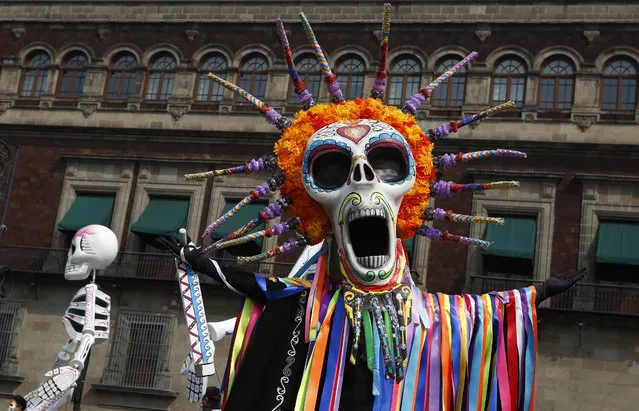 Performers in costume attend a Day of the Dead parade in Mexico City, Sunday, October 27, 2019. The parade on Sunday marks the fourth consecutive year that the city has borrowed props from the opening scene of the James Bond film, “Spectre,” in which Daniel Craig’s title character dons a skull mask as he makes his way through a crowd of revelers. (Photo by Ginnette Riquelme/AP Photo)