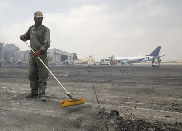 A man clears debris from the tarmac of Jinnah International Airport, after Sunday's attack by Taliban militants on Sunday, in Karachi June 10, 2014. REUTERS/Athar Hussain