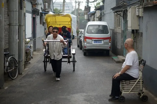 A Chinese rickshaw driver walks through an alley in Beijing on May 24, 2014. Chinese manufacturing activity saw a sharp improvement in May, hitting a five-month high, HSBC said on May 20, but it warned more government action was needed to kickstart the world's number two economy. (Photo by Wang Zhao/AFP Photo)