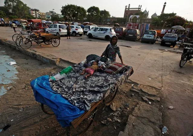 A woman pushes a cart towards the shade as her son sleeps on it on a hot summer day in the old quarters of Delhi, India June 8, 2016. (Photo by Adnan Abidi/Reuters)