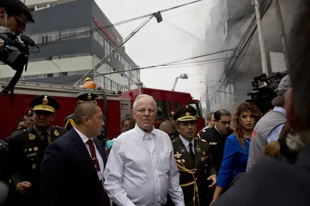Peru's President Pedro Pablo Kuczynski walks to inspect firefighting efforts at a warehouse in Lima, Peru, Friday, June 23, 2017. (Photo by Rodrigo Abd/AP Photo)