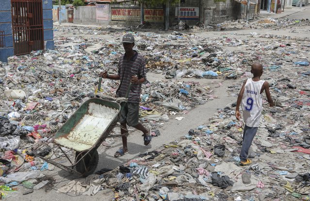 People walk down a street covered with trash in downtown Port-au-Prince, Haiti, Thursday, September 5, 2024. (Photo by Odelyn Joseph/AP Photo)