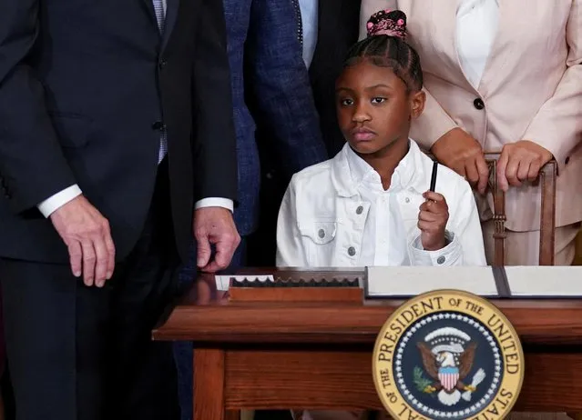 George Floyd's daughter Gianna Floyd sits at the presidential desk holding up one of the president's pens as U.S. President Joe Biden talks to the crowd from beside her after Biden signed an executive order to reform federal and local policing on the second anniversary of the death of her father George Floyd in Minneapolis police custody, in the East Room of the White House in Washington, U.S., May 25, 2022. (Photo by Kevin Lamarque/Reuters)
