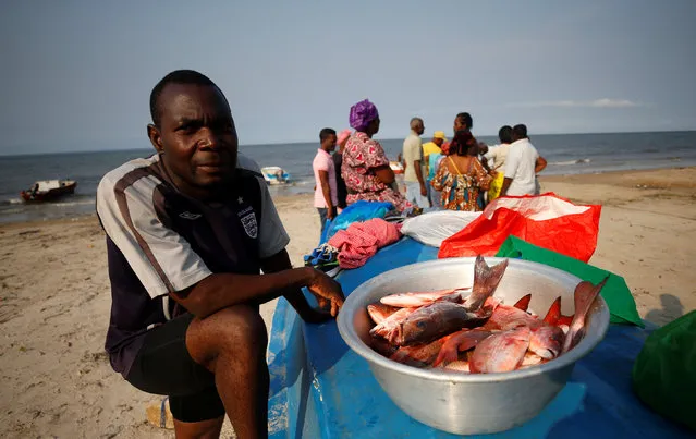A fisherman sells part of his catch on the beach in Libreville, Gabon, February 3, 2017. (Photo by Mike Hutchings/Reuters)