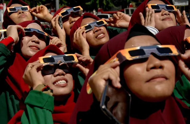 Women wearing special protective glasses observe the annular solar eclipse at mosque in Gowa, South Sulawesi, Indonesia on December 29, 2019. (Photo by Abriawan Abhe/Antara Foto via Reuters)