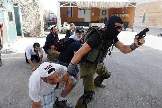 A group of tourists take part in a two hour “boot camp” experience, at “Caliber 3 Israeli Counter Terror and Security Academy” in the Gush Etzion settlement bloc south of Jerusalem in the occupied West Bank on July 13, 2017. It is part of a counter-terrorism “boot camp” organised by Caliber 3, a company set up by a colonel in the Israeli army reserves. (Photo by Nir Elias/Reuters)