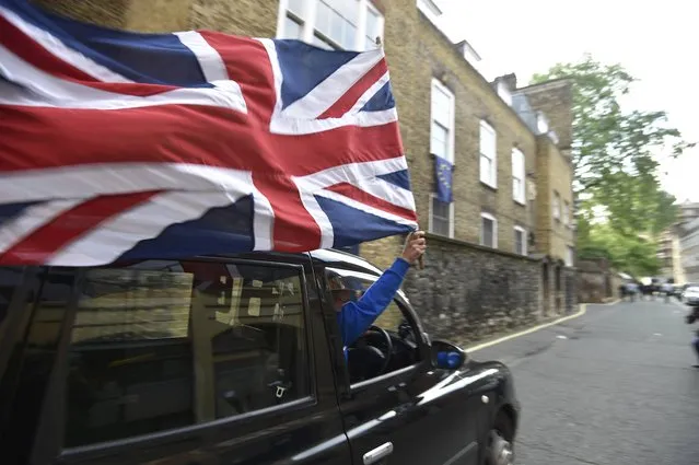 A taxi driver holds a Union flag, as he celebrates following the result of the EU referendum, in central London, Britain June 24, 2016. (Photo by Toby Melville/Reuters)