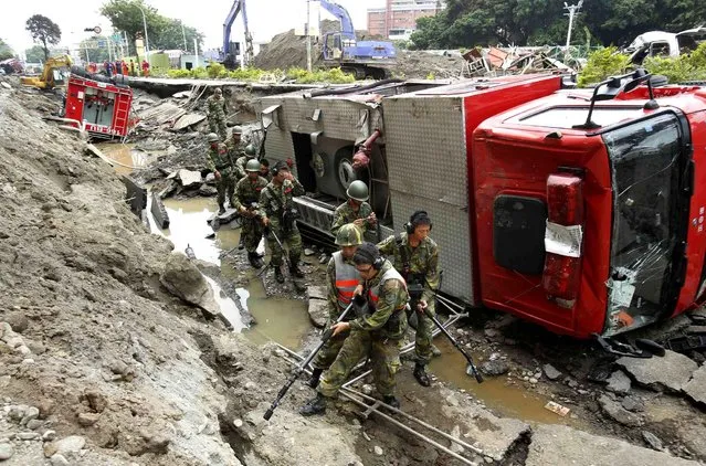 Soldiers use electronic sensors to search for missing firefighters under a line of fire trucks caught in massive gas explosions in Kaohsiung, Taiwan, Friday, August 1, 2014. A series of underground explosions about midnight Thursday and early Friday ripped through Taiwan's second-largest city, killing scores of people, Taiwan's National Fire Agency said Friday. (Photo by Wally Santana/AP Photo)