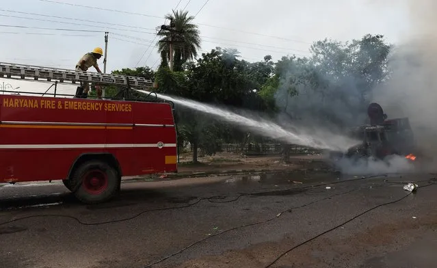 Indian firemen douse a burned media vehicle during clashes between the controversial guru's followers and security forces in Panchkula on August 25, 2017. (Photo by Money Sharma/AFP Photo)
