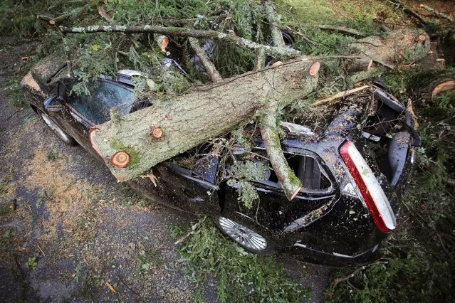 The log of a tree sits on a car after a storm in Bad Schwalbach near Frankfurt, Germany, Monday, August 11, 2014. A thunderstorm destroyed several cars and damaged buildings on Sunday evening. (Photo by Fredrik von Erichsen/AP Photo/DPA)