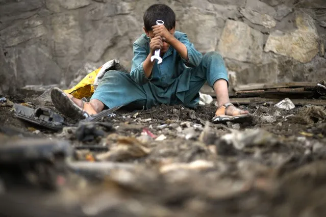 A child uses a wrench as he scavenges for scrap metal in Kabul on July 26, 2022. (Photo by Daniel Leal/AFP Photo)