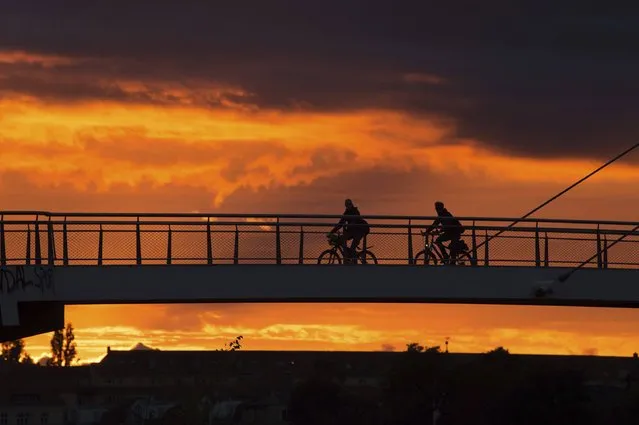 In this September 1, 2017 photo cyclists cross the Molen bridge in the light of the setting sun in Dresden, Germany. (Photo by Sebastian Kahnert/DPA via AP Photo)