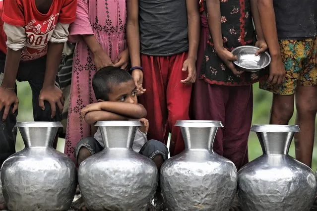 Children wait in a line as they came a long way to collect safe drinking water in a flooded area in Companiganj, Sylhet, Bangladesh on June 21, 2022. (Photo by Syed Mahamudur Rahman/NurPhoto via Getty Images)