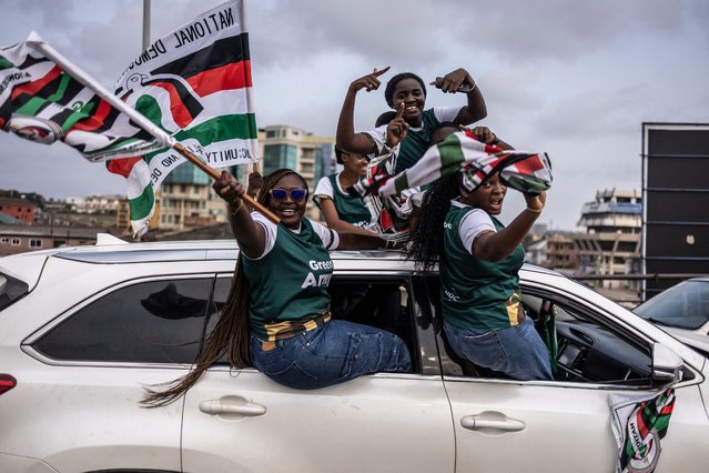 Supporters of former Ghana President and presidential candidate for the National Democratic Congress (NDC), John Mahama (unseen) rise flags of NDC political party on they suit in a car during an electoral caravan ahead of presidential election of December 7, 2024, in Accra, on December 3, 2024. The management of the economy will be key when Ghana votes on December 7 to replace President Nana Akufo-Addo who steps down after two terms in office. (Photo by Olympia de Maismont/AFP Photo)