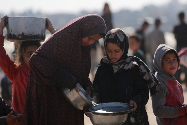 A Palestinian girl shares her portion with another girl at a distribution centre south of Khan Yunis in the southern Gaza Strip on December 17, 2024, amid the ongoing war between Israel and the Palestinian Hamas movement. (Photo by Bashar Taleb/AFP Photo)