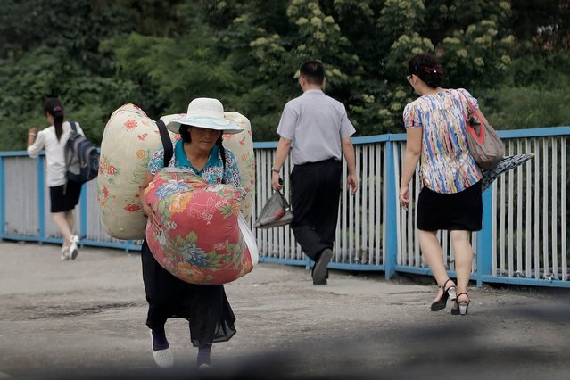 A woman carries her belongings as she walks on an overpass at the end of the workday in Pyongyang, North Korea on July 28, 2017. (Photo by Wong Maye-E/AP Photo)