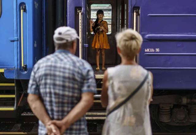 A young girl holds her dog while waving goodbye to her grandparents from an evacuation train departing Pokrovsk, Donetsk region, eastern Ukraine, Tuesday, August 2, 2022, for a safer part of the country to the west. The government issued an order to residents to leave the Donetsk region in the face of the Russian offensive as they are preparing for fall and winter and fear that many there may not have access to heating, electricity, or even clean water. (Photo by David Goldman/AP Photo)