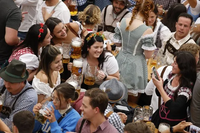 Visitors pose for pictures while holding mugs of beer during the official opening the world's largest beer festival, the 187th Oktoberfest in Munich, Germany on September 17, 2022. (Photo by Michaela Rehle/Reuters)