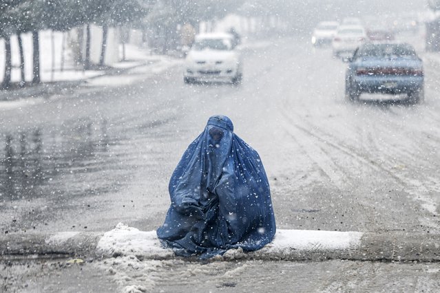 An Afghan burqa-clad woman looks for alms along a street, during the first heavy snowfall this winter in Kabul on January 2, 2025. (Photo by Wakil Kohsar/AFP Photo)