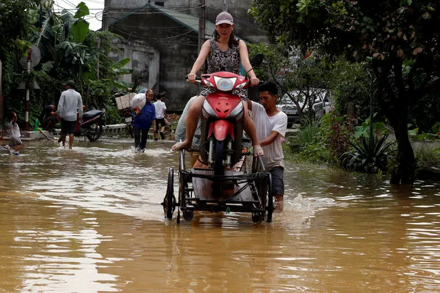 Men evacuate a woman through a flooded road after a tropical depression in Hanoi, Vietnam on Octoner 13, 2017. (Photo by Reuters/Kham)