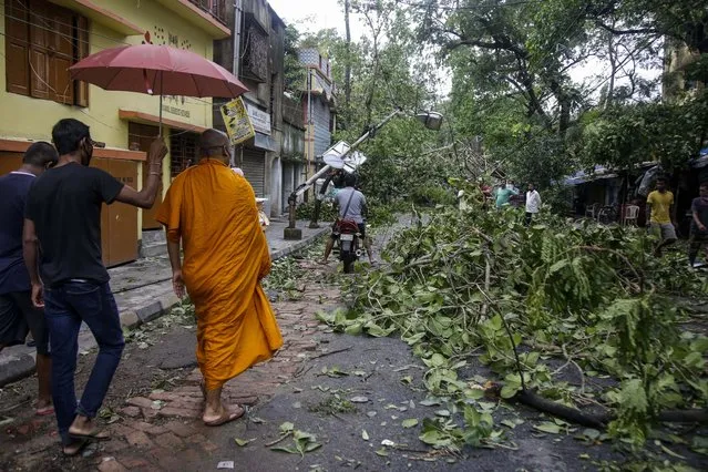 A Buddhist monk walks through a road laid with fallen trees and branches after Cyclone Amphan hit the region in Kolkata, India, Thursday, May 21, 2020. A powerful cyclone ripped through densely populated coastal India and Bangladesh, blowing off roofs and whipping up waves that swallowed embankments and bridges and left entire villages without access to fresh water, electricity and communications. (Photo by Bikas Das/AP Photo)