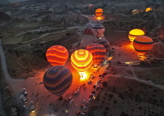 Sight-seeing hot air balloons prepare to launch in Goreme Historical National Park, east of Nevesehir (Neapolis) in the province of the same name in central Turkey's historical Cappadocia (Kapadokya) region on August 24, 2022. (Photo by Omar Haj Kadour/AFP Photo)
