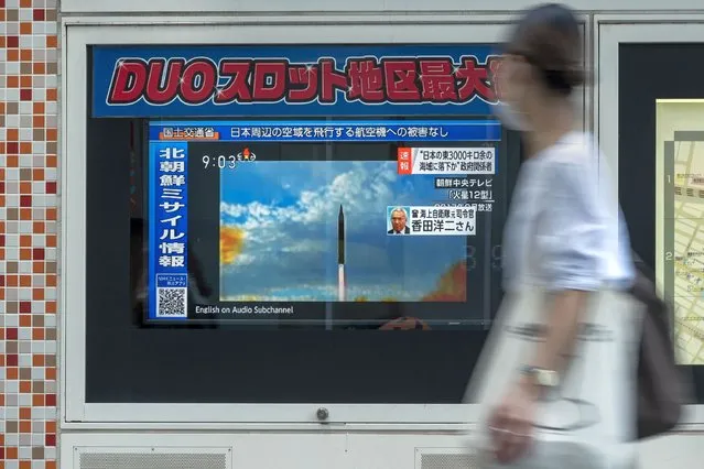 A woman walks past a public television screen in Tokyo on October 4, 2022, displaying file footage of North Korean missile launches during a broadcast about an early morning North Korean missile launch which prompted an evacuation alert when it flew over northeastern Japan. North Korea fired a mid-range ballistic missile on October 4, which flew over Japan, Seoul and Tokyo said, a significant escalation as Pyongyang ramps up its record-breaking weapons-testing blitz. (Photo by Richard A. Brooks/AFP Photo)