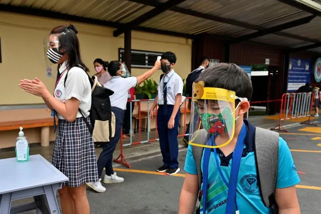 A staff member checks the temperature of a student on the first day of the reopening of the International Pioneers School in Bangkok on June 16, 2020, following its temporary closure due to the COVID-19 coronavirus epidemic. Some schools in Thailand have reopened as they adopted preventive measures such as social distancing and regular disinfection to halt the spread of the virus. (Photo by Romeo Gacad/AFP Photo)