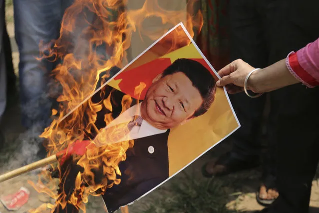 A Bharatiya Janata Party activist burns a photograph of Chinese President Xi Jinping during a protest in Jammu, India, Wednesday, July.1, 2020. Indian TikTok users awoke Tuesday to a notice from the popular short-video app saying their data would be transferred to an Irish subsidiary, a response to India's ban on dozens of Chinese apps amid a military standoff between the two countries. The quick workaround showed the ban was largely symbolic since the apps can’t be automatically erased from devices where they are already downloaded, and is a response to a border clash with China where 20 Indian soldiers died earlier this month, digital experts said. (Photo by Channi Anand/AP Photo)