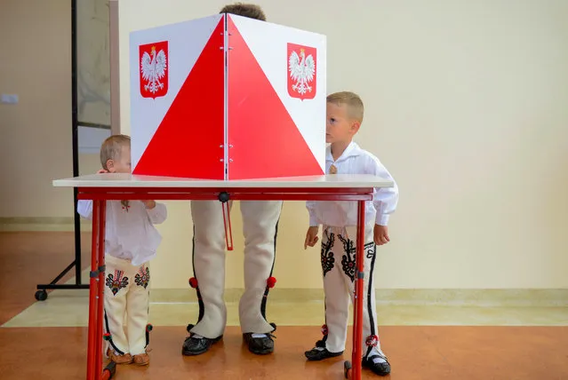 A man in traditional clothes is watched by his young boys as he sits in the voting booth on July 12, 2020 in Zab near Zakopane, during the second round of Poland's presidential election. Poles began voting on on July 12, 2020 in a knife-edge presidential election between a populist incumbent closely allied with the US President and a europhile liberal who wants to restore ties with Brussels. (Photo by Bartosz Siedlik/AFP Photo)