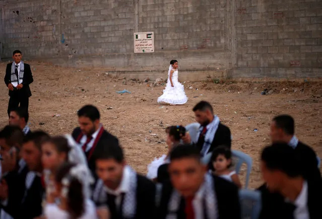 A Palestinian girl walks as grooms sit on chairs during a mass wedding for 340 couples organised by Hamas movement in Beit Lahiya town in the northern Gaza Strip July 24, 2016. (Photo by Mohammed Salem/Reuters)