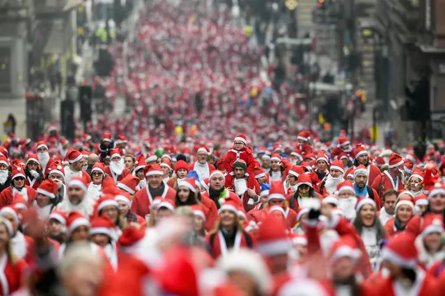 Over eight thousand members of the public take part in Glasgow's annual Santa dash make their way up St Vincent Street on December 10, 2017 in Glasgow, Scotland. The Santa Dash has been held since 2006 and this year is the 11th anniversary event, in total the event has raised over £200,000 for charities working in and around Glasgow. (Photo by Jeff J. Mitchell/Getty Images)
