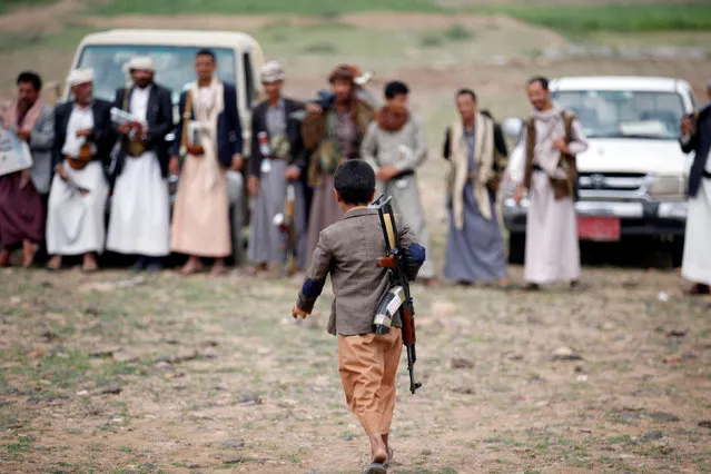 An armed boy walks as he attends a gathering held by tribesmen loyal to the Houthi movement to show support to a political council formed by the movement and the General People's Congress party to unilaterally rule Yemen by both groups in Sanaa, August 14, 2016. (Photo by Khaled Abdullah/Reuters)