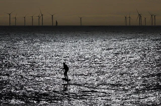 A foil electric surfer practice in front of the Saint-Nazaire offshore wind farm, during a warm autumn day in Pornichet, France on October 26, 2022. (Photo by Stephane Mahe/Reuters)
