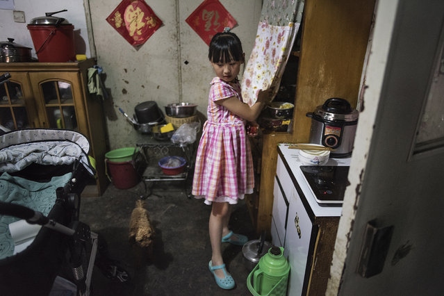 A girl prepares food in her basement dwelling in Beijing on May 22, 2016. Beijing's real estate market is one of China's  most expensive and that has resulted in thousands illegally living in basement “apartments”. They are known as “Shuzu”, or “rat tribe”. The Beijing government has cracked down, but  residents say that as soon as they clear out a basement, the “Shuzu”, move back in within days. (Photo by Michael Robinson Chavez/The Washington Post)