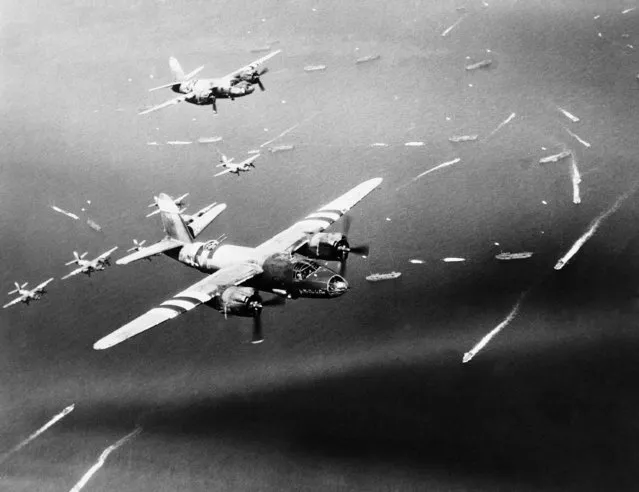 Marauders of the 9th Air Force bombardment group, fly over units of the Allied fleet as they approach landfall on the French coast, on June 21, 1944. Marauder groups such as these, fly constantly in close support of our advancing group forces. Their targets are enemy gun positions, bridges, railroad and highway junctions, convoys and troops concentrations. (Photo by AP Photo)