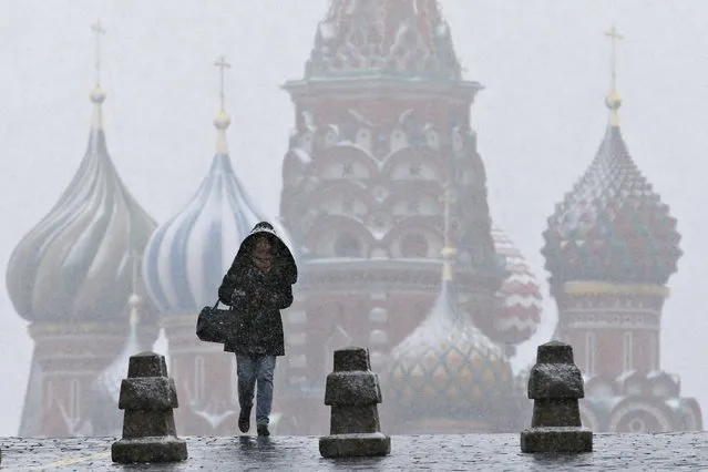 A woman walks along Red Square under snowfall, with St. Basil's Cathedral seen in the background, in central Moscow, Russia, October 9, 2015. (Photo by Maxim Zmeyev/Reuters)