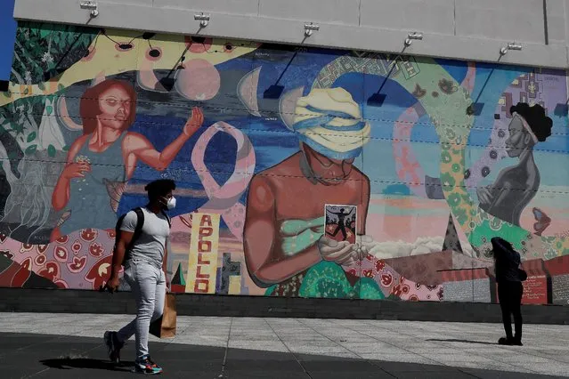 A man wearing a protective face covering walks by a mural  in the Harlem neighborhood of New York City, New York, U.S., July 9, 2020. (Photo by Shannon Stapleton/Reuters)