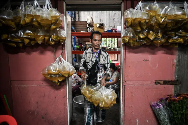This photo taken on August 17, 2022, in Yangon, shows a volunteer preparing free meals to distribute. (Photo by AFP Photo/Stringer)