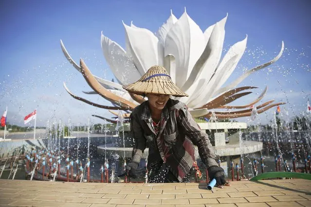 A girl wearing a hat and tanaka paste on her face gets out of a fountain after releasing water in it at the one of main intersections of Naypyitaw November 10, 2014. Leaders from ASEAN, East Asian and other countries will gather for the ASEAN summit this week in Myanmar's capital, Naypyitaw. United States President Barak Obama is scheduled to attend. (Photo by Damir Sagolj/Reuters)